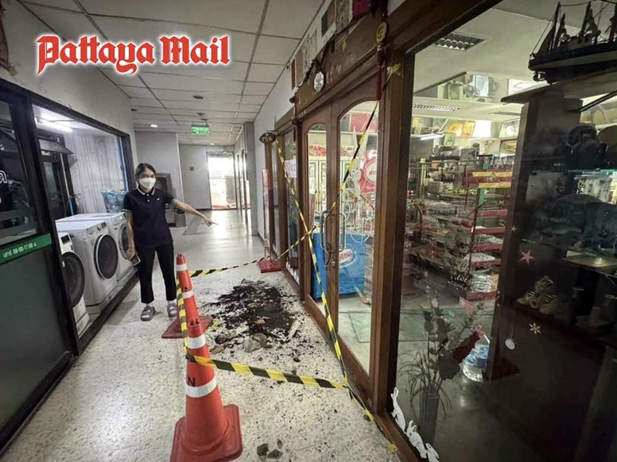 A resident wearing a face mask points to a taped-off section of the shophouse arcade inside the apartment building in Soi Phatthanakan 43, Bangkok, where the confrontation took place
