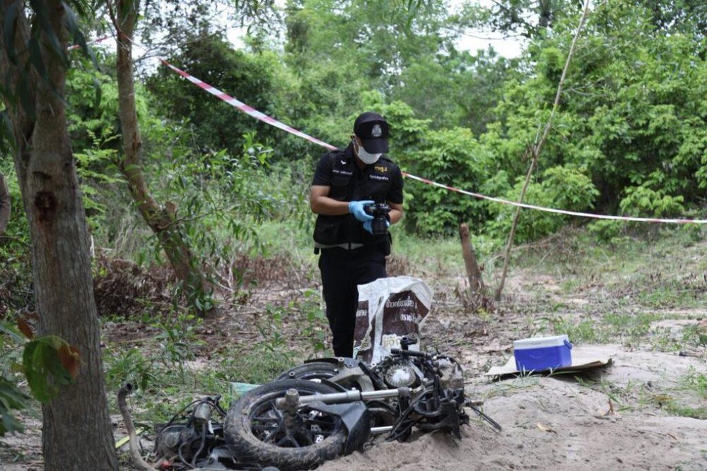 Pattaya news photo of a Thai police forensic officer photographing the dismantled Honda ADV motorcycle recovered from a buried pit in Chonburi near Pattaya Thailand