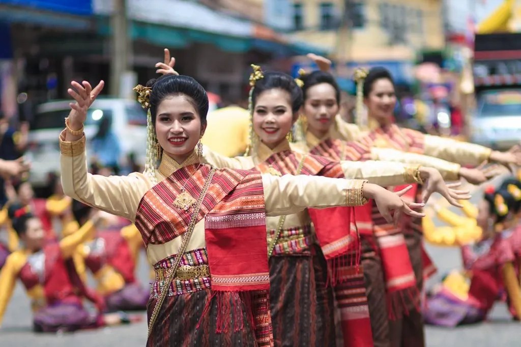 Dancers in traditional Isan silk and hand-woven sashes performing in formation on the street during the Ubon Ratchathani candle procession