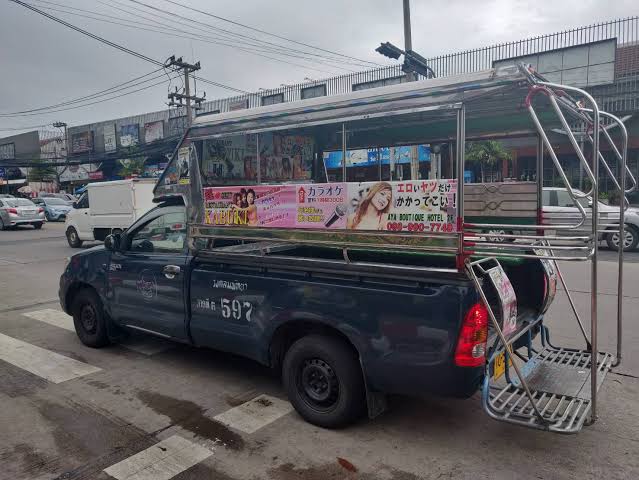A blue Pattaya baht bus parked at the roadside