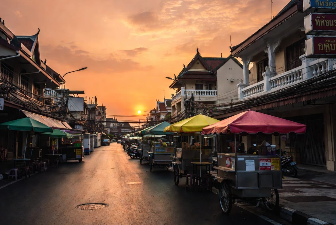 Street-food carts along an old shophouse street at sunset in the Bang Rak area