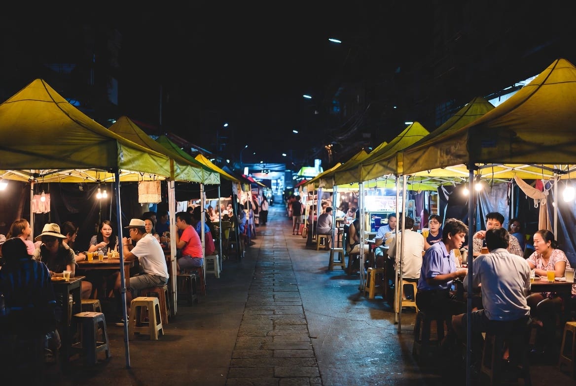 Food tents and tables filling a narrow soi after dark