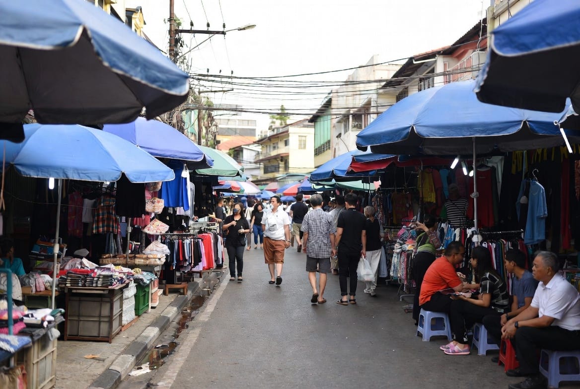 Market umbrellas and food stalls along the leafy main soi of Ari