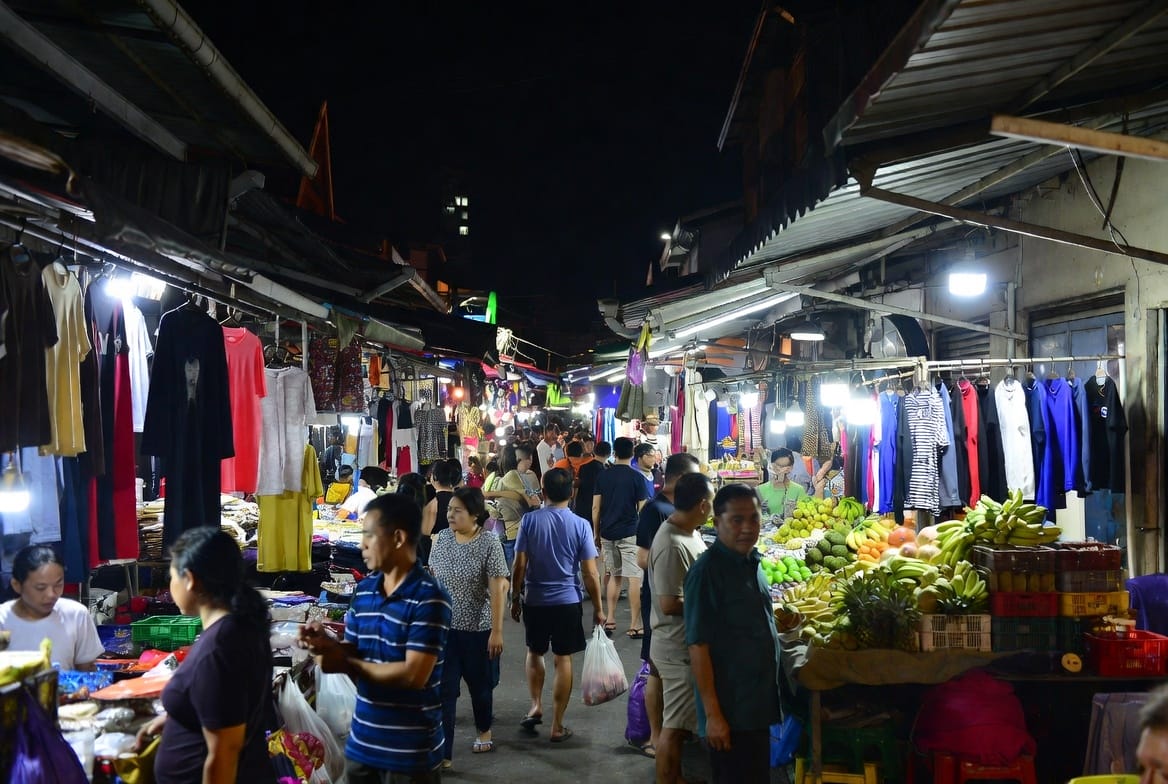 Mixed market stalls with clothes and fruit in the streets around Sam Yan