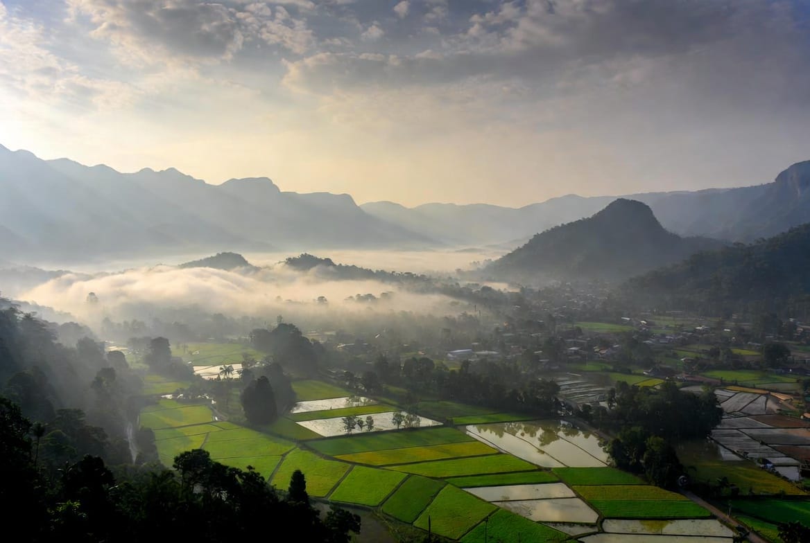 Misty morning over the Pai valley with rice fields and mountains in northern Thailand