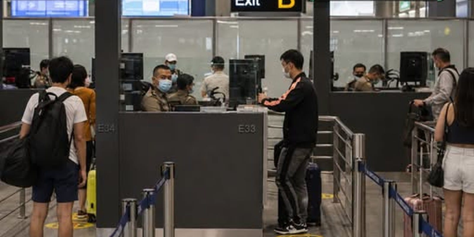 Travellers queueing at immigration passport control counters at a Thai airport