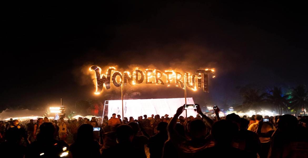 Wonderfruit Festival iconic burning sign and a large crowd at night in Thailand